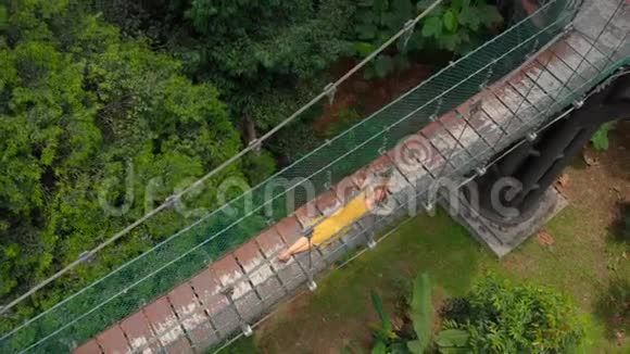 一名年轻女子的空中射击躺在丛林上空的吊桥上东南亚概念旅行视频的预览图