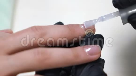 美容师在女性指甲上涂上底衣水疗沙龙服务视频的预览图