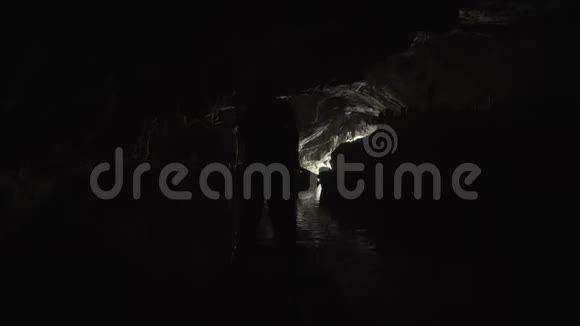 一个人的剪影漂浮在一个黑暗的洞穴里在竹筏上朝出口走去视频的预览图