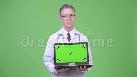 快乐成熟的男医生在展示笔记本电脑时思考的肖像视频的预览图