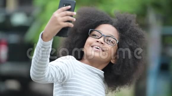 年轻可爱的非洲女孩带着非洲头发视频在户外街头打电话视频的预览图