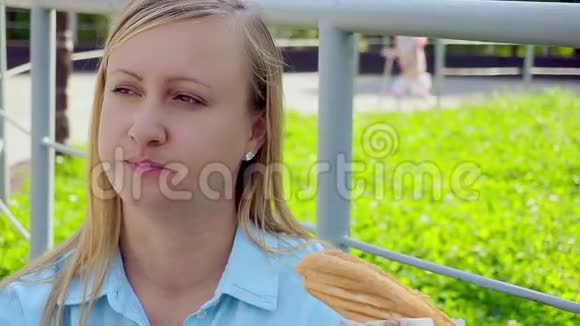 中年妇女在公园的街上吃热狗特写视频的预览图