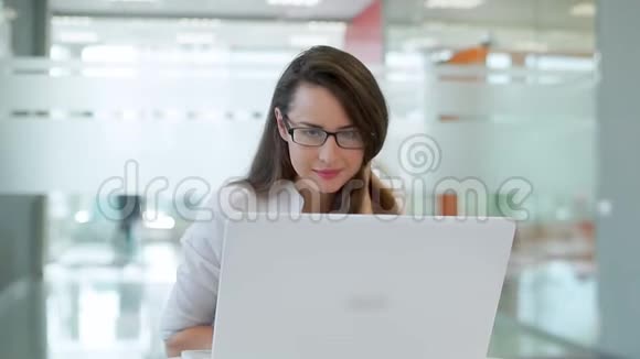 那个女孩在一间宽敞明亮的办公室里在一张有笔记本电脑的桌子上她看着相机微笑视频的预览图