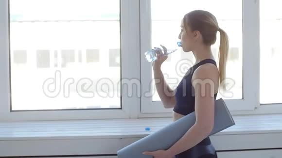 健身理念年轻女子在白色室内运动后饮用水视频的预览图