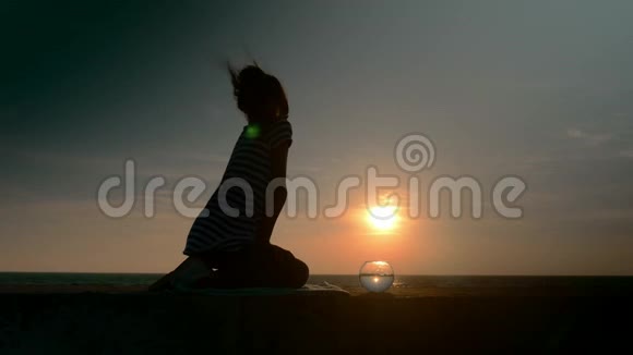 剪影小女孩在夕阳下的海景背景下拍摄小鱼缸看小鱼概念视频的预览图