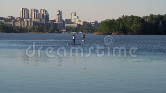 长镜头女孩和男人在城市的背景下学会在河上游泳视频的预览图