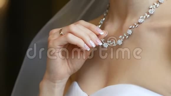 新娘用精致的手拿着项链项链在脖子上新娘结婚的早晨广告珠宝视频的预览图