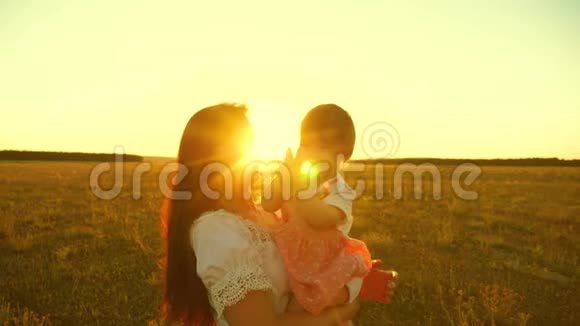小宝宝在日落时坐在笑妈妈的手上啃拳头慢动作视频的预览图
