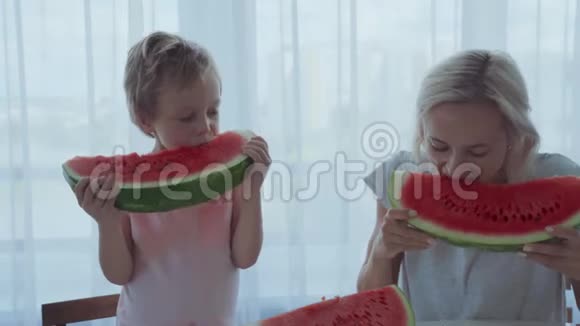 快乐的男孩喝着红色的西瓜吃着牙齿下流淌的果汁视频的预览图