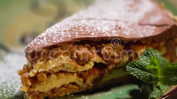 美味可口的一块蛋糕里面有坚果和巧克力在薄荷旁边的盘子里撒上甜粉视频的预览图
