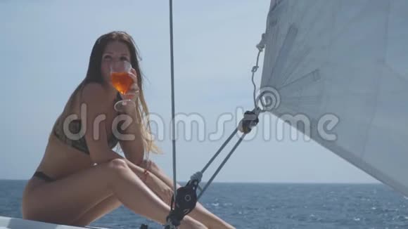 一个漂亮的女孩坐在游艇甲板上喝香槟视频的预览图