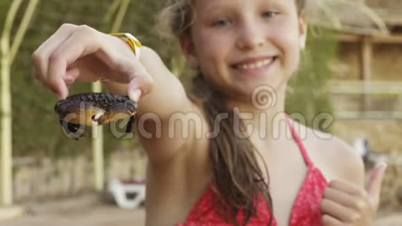 快乐的女孩抱着一只螃蟹在海滩上展示视频的预览图