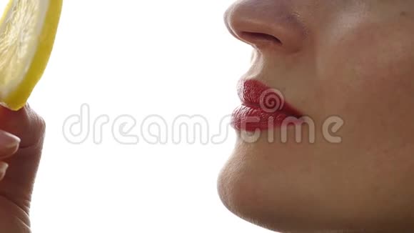 女人舔和吃多汁的柠檬特写嘴唇在白色的背景慢动作视频的预览图