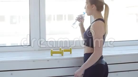健身理念年轻女子在白色室内运动后饮用水视频的预览图
