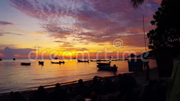 泰国海滩上观看日落的人剪影带船座视频的预览图