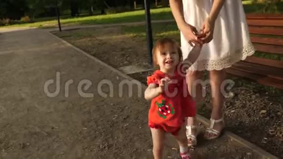 小宝宝正在学着牵着妈妈的手微笑着走在公园的小路上视频的预览图