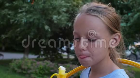 在夏季公园里小女孩吃冰淇淋舔嘴唇视频的预览图