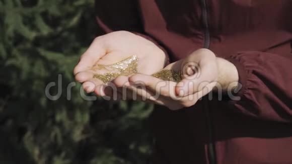 一个人用手在大自然的背景下吹出金光视频的预览图