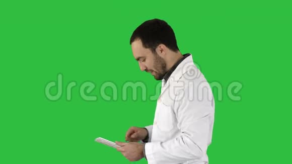 男性医生行走和使用数字平板在绿色屏幕上的肖像色度键视频的预览图