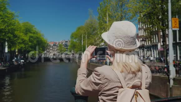 一位戴着帽子和背包的女游客描绘了阿姆斯特丹运河的美丽景色旅游业视频的预览图