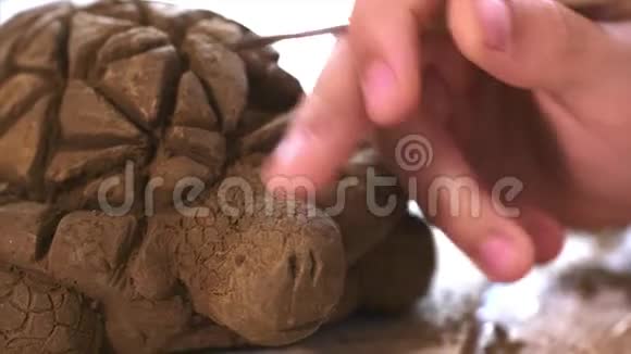 孩子们正在用粘土在手工制作的乌龟玩具上刮破鳞片的纹理视频的预览图