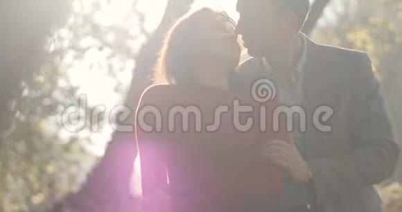4k秋天的气氛男人从背后温柔地拥抱女人用金色的叶子亲吻她站在秋天的公园里视频的预览图