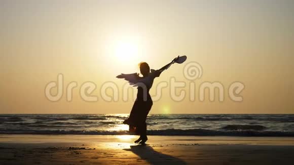 年轻女孩的剪影带着天使的翅膀在日落时缓慢地跳舞视频的预览图