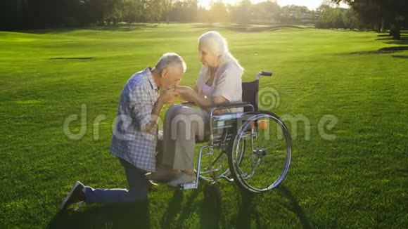 丈夫在轮椅上温柔地亲吻妻子的双手视频的预览图