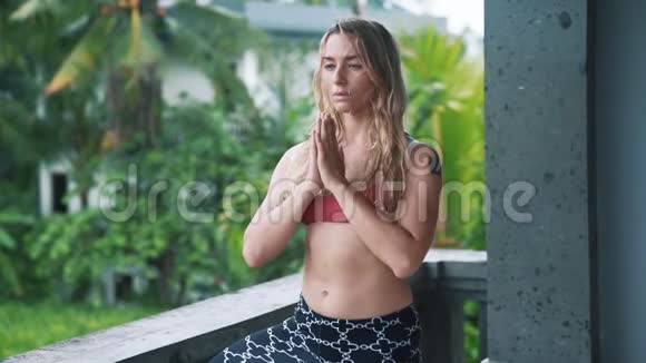 年轻女性做瑜伽运动在户外伸展身体背景是绿色植物视频的预览图