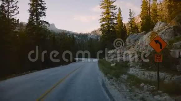 汽车中的POV摄像机沿着美丽的森林山路在日落的岩石之间移动在约塞米蒂公园缓慢的运动视频的预览图