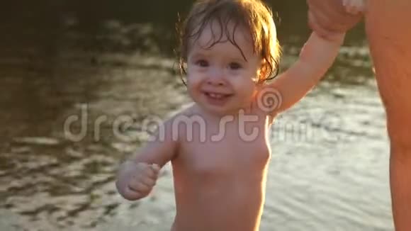 快乐的孩子笑着牵着爸爸的手沿着海滩散步特写视频的预览图