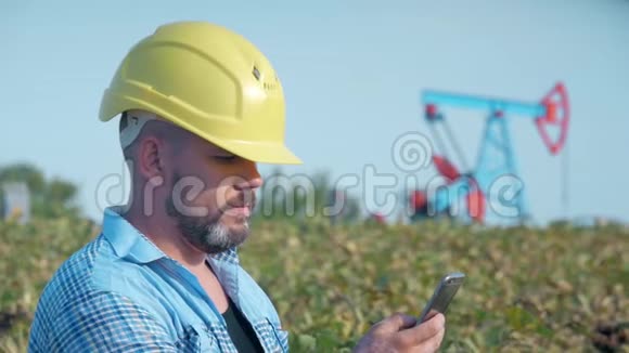 工程师油工用手机工作油钻现场泵千斤顶油田油工在干活这就是视频的预览图