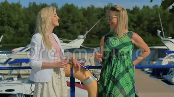 两个时髦的女人站在游艇俱乐部的背景下谈论和喝香槟视频的预览图