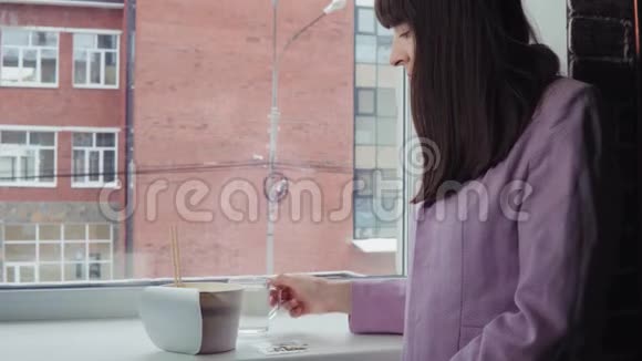 女商人在窗前准备方便面靠在一座砖楼上视频的预览图