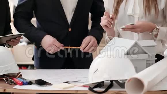 工人们积极地讨论和签署一份草稿躺在桌子上那个人犹豫地转动手中的铅笔在上面视频的预览图