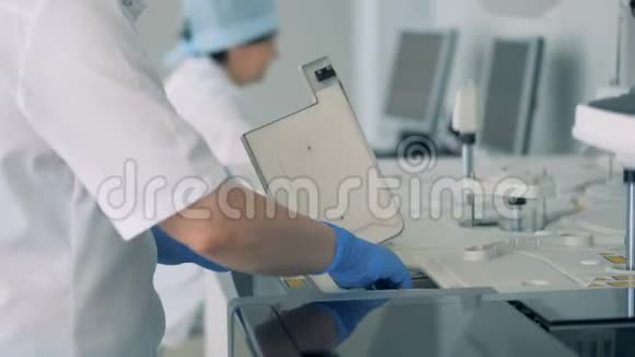 护士在一个现代化的实验室里用特殊的机器做测试后拿起瓶子样本视频的预览图