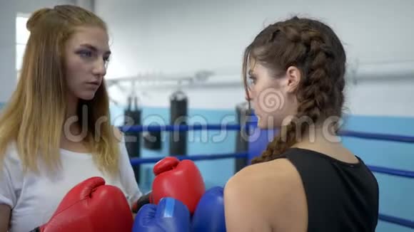 拳击手套中的年轻女孩在体育馆拳击前愤怒地看着对方的眼睛视频的预览图