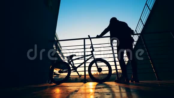 在日落背景下骑自行车的自行车活跃的青少年剪影视频的预览图