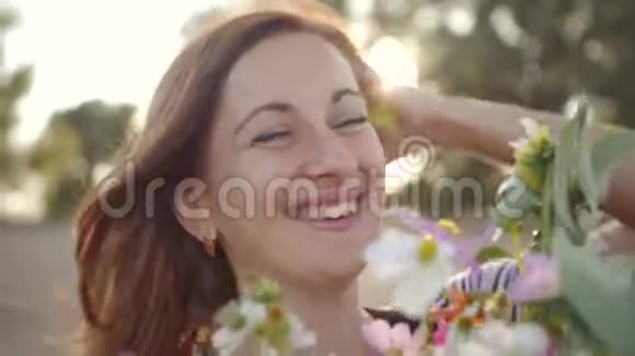 美丽的年轻女子微笑着拿着一束野花的肖像视频的预览图