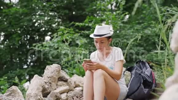 一个戴着白帽子的女人正在智能手机上输入一条信息女孩坐在台阶上拨短信视频的预览图