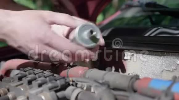 一个独立取代他车里的LPG过滤器的人的手的特写视频的预览图