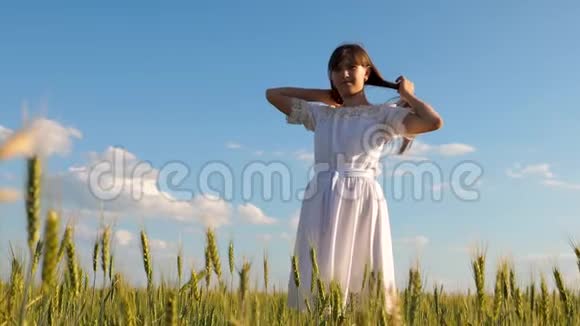 美丽的女孩用手纠正长发用小麦对着蓝天微笑慢动作视频的预览图