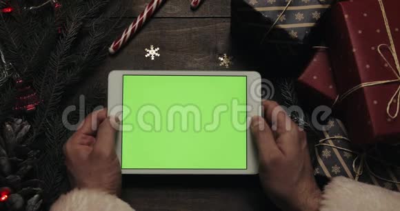 圣诞老人手里拿着绿色屏幕的白色平板电脑上的书页铬钥匙上景水平视频的预览图