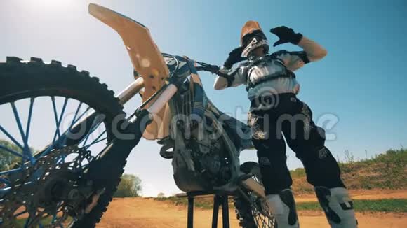 摩托车手摘下头盔挂在摩托车上视频的预览图