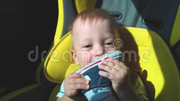一个可爱的小婴儿坐在汽车座椅上微笑和旅行的快乐视频的预览图