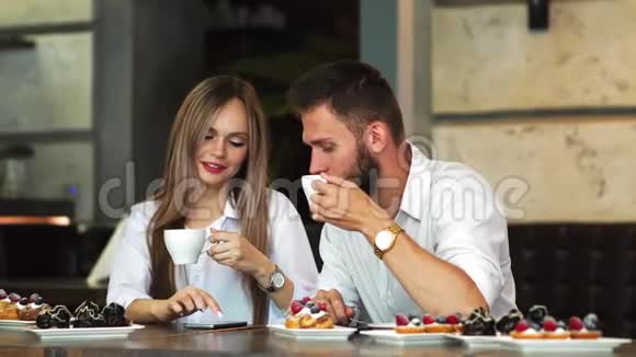 酒吧里的男人和女人喝咖啡用手机视频的预览图