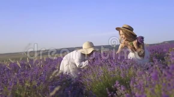 年轻的母亲给她的女儿一束淡紫色的花在一片芬芳的田野里缓慢地活动着视频的预览图