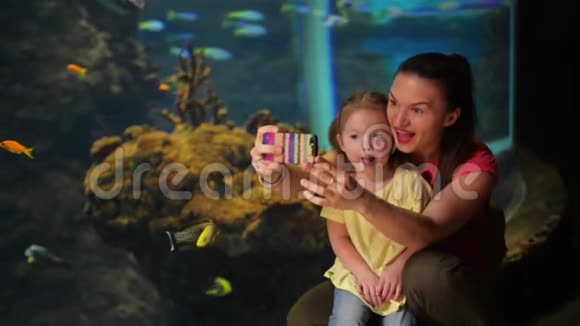快乐的母亲和女儿正在自拍有鱼的水族馆就在后台他们有很多乐趣这位母亲视频的预览图