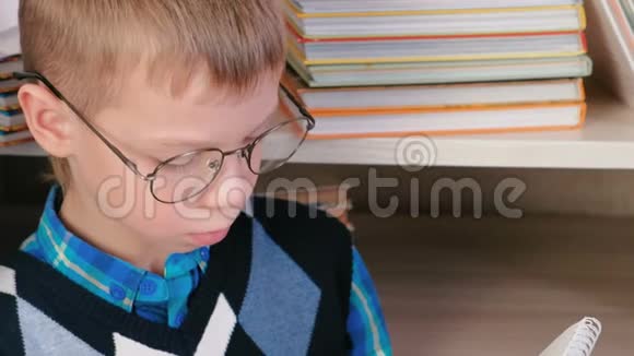 七岁戴眼镜的男孩在一本坐在书中的素描书中画了一些东西特写的脸视频的预览图