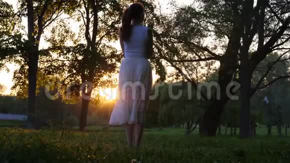 穿着白色衣服的女士在公园欣赏日落视频的预览图